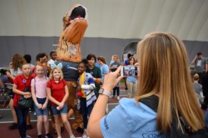 woman taking pictures of kids and someone in a dinosaur outfit